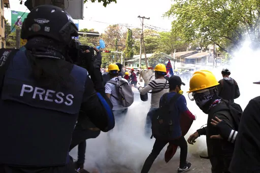 A photographer wearing a protective vest with a 'press' sign at the back films an anti-military government protest being dispersed with tear gas by security forces in Sanchaung township in Yangon, Myanmar on March 3, 2021. Since Myanmar's military dismissed the results of democratic elections and seized power on Feb. 1, 2021, peaceful nationwide protests and violent crackdowns by security forces have spiraled into a nationwide humanitarian crisis. (AP Photo)