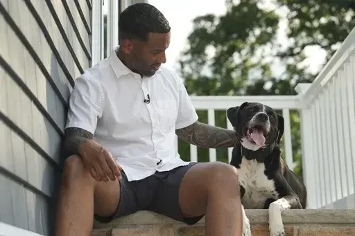 Dave Crenshaw poses for a photo with his service dog, Doc, in front of his home in Kearny, N.J., on Monday, June 3, 2024. (AP Photo/Mary Conlon)