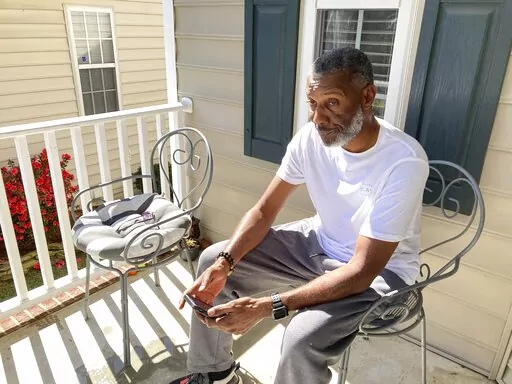 Tracey Howard, husband of Nicole Connors who was fatally shot on Thursday, Oct. 13, 2022, sits on the porch of his Raleigh, N.C., home on Friday, Oct. 14. On Thursday, a 15-year-old boy fatally shot two people in the streets of a middle-class Raleigh neighborhood, then fled toward a popular walking trail where he opened fire, killing three more people and wounding two others in an attack that left the city reeling and authorities searching for a motive, police said. (AP Photo/Allen G. Breed)