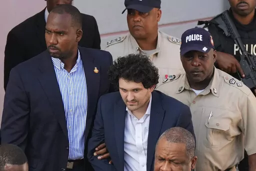 FTX founder Sam Bankman-Fried, center, is escorted out of Magistrate Court into a Corrections van, following a hearing in Nassau, Bahamas, Monday, Dec. 19, 2022. (AP Photo/Rebecca Blackwell)