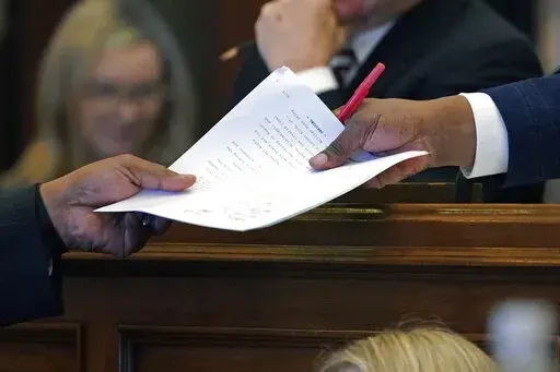 Mississippi Senate Press Secretary Arnold Lindsay, right, receives a resolution from a senator at the Mississippi Capitol in Jackson, Miss., Wednesday, Feb. 23, 2022. (AP Photo/Rogelio V. Solis)