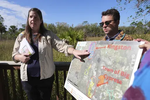 Amber Crooks, environmental policy manager with the Conservancy of Southwest Florida, left, and Michael McGrath of the Sierra Club, right, hold a map showing proposed developments at the Panther National Wildlife Refuge in Southwest Florida, Wednesday, Jan. 15, 2025. (AP Photo/Lynne Sladky)