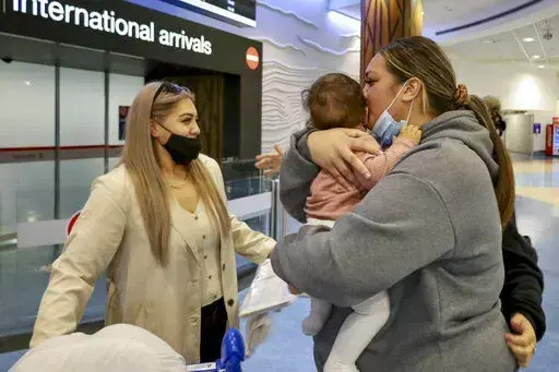 Families embrace after a flight from Los Angeles arrived at Auckland International Airport as New Zealand's border opened for visa-waiver countries Monday, May 2, 2022. New Zealand welcomed tourists from the U.S., Canada, Britain, Japan and more than 50 other countries for the first time in more than two years as it dropped most of its remaining pandemic border restrictions. (Jed Bradley/New Zealand Herald via AP)