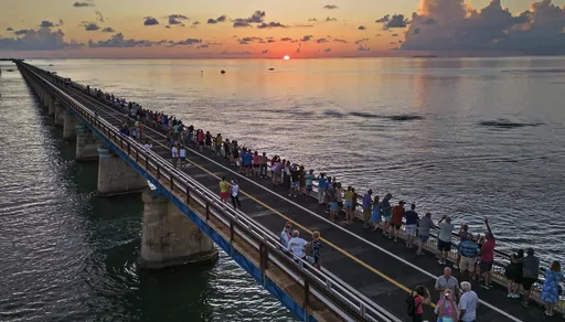 In this aerial photo provided by the Florida Keys News Bureau, attendees watch and toast the sunset at a Florida Keys bicentennial celebration, Friday, May 19, 2023, on the restored Old Seven Mile Bridge in Marathon, Fla. The sunset gathering was among a series of Keys events being staged to mark the 200th anniversary, on July 3, of the Florida Territorial Legislature's 1823 founding of Monroe County, containing the entire island chain. The old bridge was originally part of Henry Flagler's Flori