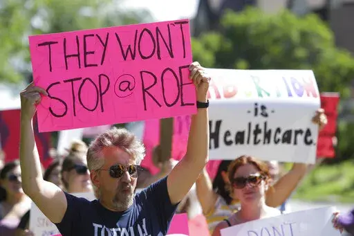 A man holds a sign as community members walk around Vander Veer Park during a march following the Supreme Court decision to overturn Roe v. Wade, June 26, 2022, in Davenport, Iowa. Democrats and their aligned groups raised more than $80 million in the week after the Supreme Court stripped away a woman’s constitutional right to have an abortion. The flood of cash offers one of the first tangible signs of how the ruling may energize voters. (Nikos Frazier/Quad City Times via AP)