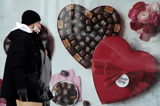 A man passes a Fannie May chocolate shop in downtown Chicago on Valentine's Day, Feb. 14, 2021. Valentine's Day is meant to celebrate romance and the depths of feeling we have for loved ones. So it may be surprising how much Valentine's shopping is done at the last minute. (AP Photo/Nam Y. Huh, File)