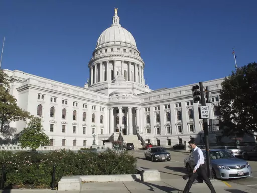 A man walks by the Wisconsin Capitol, Oct. 10, 2012, in Madison, Wis. On Wednesday, Oct. 4, 2023, a man illegally brought a loaded handgun into the Wisconsin Capitol, demanding to see Gov. Tony Evers, and returned at night with an assault rifle after posting bail, police said Thursday, Oct. 5. (AP Photo/Scott Bauer, File)