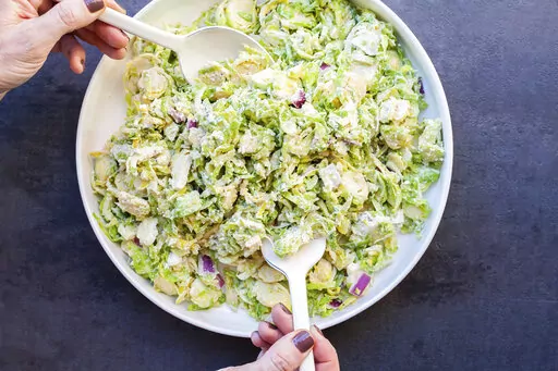 A recipe for Creamy Brussels Sprouts Slaw, with a mayonnaise-based dressing spiked with citrus juice, onions, mustard, and Parmesan cheese, appears in New York in January 2018. (Carrie Crow via AP)