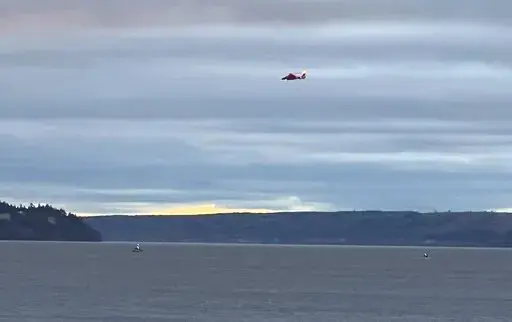 A Coast Guard helicopter searches the area where a floatplane crashed near Whidbey Island, Wash., Sunday, Sept. 4, 2022. (Courtney Riffkin/The Seattle Times via AP)