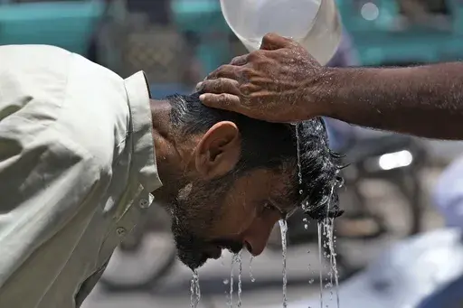 A volunteer pours water to cool a man off during a hot day in Karachi, Pakistan, May 21, 2024. (AP Photo/Fareed Khan, File)