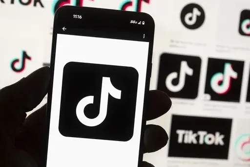 The TikTok logo is displayed on a mobile phone in front of a computer screen, Oct. 14, 2022, in Boston. TikTok will begin labeling content created using artificial intelligence when it's uploaded from certain platforms. TikTok says its efforts are an attempt to combat misinformation from being spread on its social media platform. The announcement came on ABC's “Good Morning America” on Thursday, May 9, 2024. (AP Photo/Michael Dwyer, File)