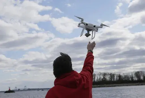 In this April 29, 2018, file photo, a drone operator helps to retrieve a drone after photographing over Hart Island in New York. (AP Photo/Seth Wenig, File)