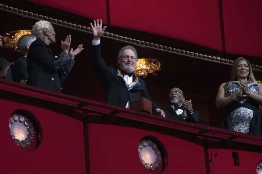 2023 Kennedy Center Honoree, comedian Billy Crystal, center, waves as he is applauded by fellow honorees Dionne Warwick and Queen Latifah, at the 46th Kennedy Center Honors at the John F. Kennedy Center for the Performing Arts in Washington, Sunday, Dec. 3, 2023. (AP Photo/Manuel Balce Ceneta)