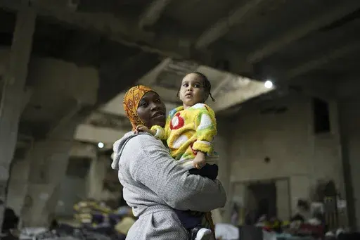 Sierra Leonean migrant worker Isatta Bah, 24, smiles as she holds her daughter, Blessing, one year old, during an interview with The Associated Press while waiting to be repatriated back home, as they are sheltered at a former car dealership in Hazmieh, east of Beirut, Lebanon, Wednesday, Dec. 4, 2024. (AP Photo/Hassan Ammar)