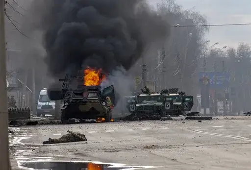 A Russian armored personnel carrier burns amid damaged and abandoned light utility vehicles after fighting in Kharkiv, the country's second-largest city in Ukraine, Feb. 27, 2022. Three months after it invaded Ukraine hoping to overtake the country in a blitz, Russia has bogged down in what increasingly looks like a war of attrition with no end in sight. (AP Photo/Marienko Andrew, File)