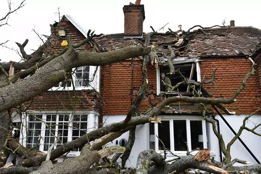 Sven Good, 23, looks out from his bedroom window at the damage caused to the family home a day after a 400-year-old oak tree in the garden was uprooted by Storm Eunice, in Stondon Massey, near Brentwood, Essex, England, Saturday Feb. 19, 2022. Crews cleared fallen trees and worked to restore power to about 400,000 people in Britain as Western Europe cleaned up Saturday after one of the most damaging storms in years. At least 12 people were killed, many by falling trees, in Ireland, Britain, Belg