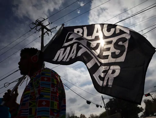 In this Dec. 12, 2020, file photo, MD Crawford carries a Black Lives Matter flag before a march in La Marque, Texas to protest the shooting of Joshua Feast, 22, by a La Marque police officer. The Black Lives Matter Global Network Foundation launched a new relief fund Monday, Dec. 12, 2022 aimed at Black college students, alumni and dropouts overburdened by mounting education costs and the student loan debt crisis. (Stuart Villanueva /The Galveston County Daily News via AP, File)