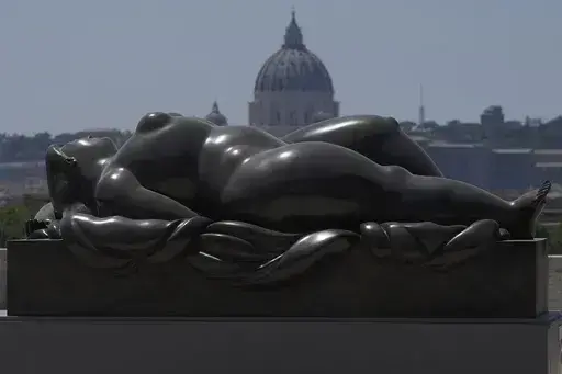 Botero's "Sleeping Venus" sculpture, installed in Rome's Pincio Terrace, Friday, July 19, 2024, appears to be in front of St. Peter's Basilica at The Vatican. Rome's storied streets and piazzas have become a vibrant canvas for Fernando Botero's exuberant sculptures, turning the city into an open-air museum of voluminous forms and daring artistry. (AP Photo/Gregorio Borgia)