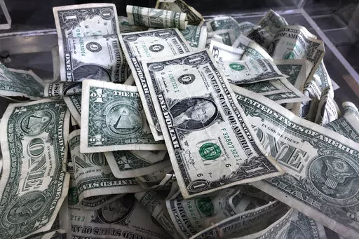 In this April 3, 2019, file photo a tip box is filled with U.S. currency in New York. Deciding how to prioritize different savings goals can be overwhelming, but financial experts recommend ordering them by urgency. Most people need an emergency fund first, followed by other goals such as saving enough for retirement, buying a home, traveling, saving for college and paying off debt. (AP Photo/Mark Lennihan, File)