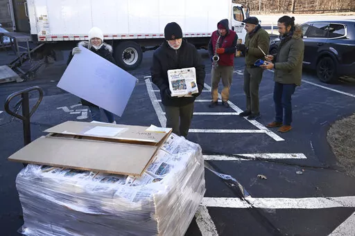 Andy Thibault, Editor and Publisher of The Winsted Citizen, carries the first bundle of papers off a pallet as Advertising and Circulation Director Rosemary Scanlon holds the first print press plate while a group of musicians play behind them after the arrival of the first delivery of the paper on, Friday, Feb. 3, 2023, in Winsted, Conn. At a time that local newspapers are dying at an alarming rate, longtime activist Ralph Nader is helping give birth to one. Nader put up $15,000 to help launch T