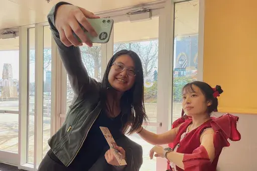 This photo provided by Fu Ting shows an audience member taking a selfie with Hoff Xu, who cosplayed a movie character before a screening of the movie Ne Zha 2 on IMAX screen in Columbia Md., on March 1. (Fu Ting via AP)