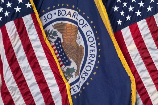 The flag of the Federal Reserve hangs between American flags at a news conference following a Federal Open Market Committee meeting on July 26, 2023 in Washington. On Wednesday, the Federal Reserve releases minutes from the July meeting when it raised its benchmark borrowing rate by another quarter point to 5.4%, the highest level in 22 years. (AP Photo/Nathan Howard, File)
