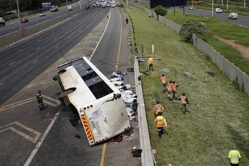 Emergency officials walk next to a bus that overturned on a highway in Johannesburg, South Africa, Tuesday, March 11, 2025, killing multiple people and injuring some. (AP Photo/Alfonso Nqunjana)