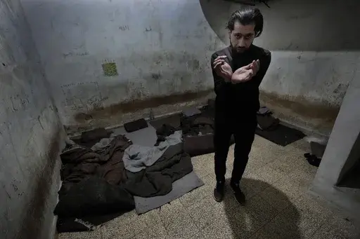Abdullah Zahra demonstrates how he was tortured in a cell at Branch 215, a detention facility run by military intelligence during Bashar Assad's regime, in Damascus, Syria, on Tuesday, Dec. 17, 2024. (AP Photo/Hussein Malla)