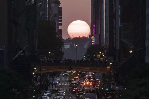 FILE — The sun sets between buildings along 42nd Street in New York during a phenomenon known as Manhattanhenge, May 30, 2023. Wednesday, July 12, 2023, and Thursday, July 13, 2023 are the last two days of Manhattanhenge for the year, when jaded New Yorkers spill onto the streets to watch the sun set between the buildings that line the city's east-west corridors. But the forecast calls for clouds so there may not be much of a show. (AP Photo/Yuki Iwamura, File)
