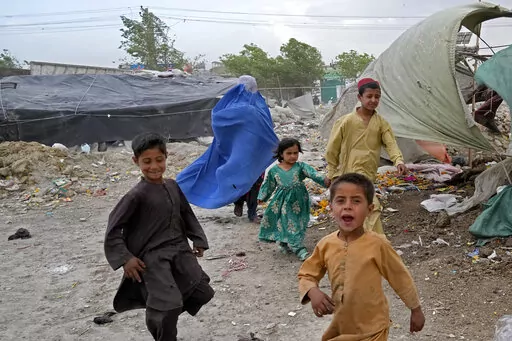 A woman wearing a burka and her children walk in front of their house in Kabul, Afghanistan, Sunday, May 8, 2022. Afghan women are furious and fearful over a recent decree by the country's Taliban leaders that reinstated the burqa and similar outfits as mandatory for them in public. But some are defying the strict interpretation of Islamic dress codes, venturing out with less restrictive versions than that which the Taliban demanded — outfits that only reveal their eyes. (AP Photo/Ebrahim Noro