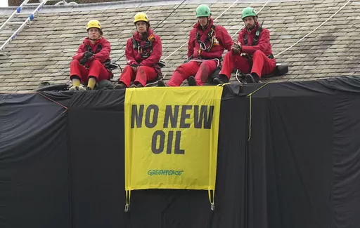 Greenpeace activists sit on the roof of Britain's Prime Minister Rishi Sunak's house in Richmond, North Yorkshire, England, after covering it in black fabric, Thursday Aug. 3, 2023. Greenpeace demonstrators draped the country estate of British Prime Minister Rishi Sunak in black fabric Thursday to protest his plan to expand oil and gas drilling in the North Sea. (Danny Lawson/PA via AP)