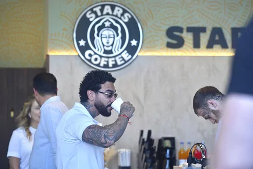 Russian singer and entrepreneur Timur Yunusov, better known as Timati, drinks coffee at a newly opened Stars Coffee coffee shop in the former location of the Starbucks coffee shop in Moscow, Russia, Thursday, Aug. 18, 2022. A new chain of coffee shops opens Thursday in Moscow, after Russian singer and entrepreneur Timur Yunusov, better known as Timati, together with Russian restaurateur Anton Pinskiy bought the Starbucks stores following company's withdrawal from Russia. (AP Photo/Dmitry Serebry
