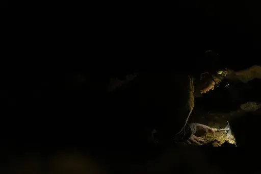 Takamatsu Gushiken uses a hand hoe to delicately move dirt in a cave while searching for the remains of those who died during the Battle of Okinawa towards the end of the World War II in 1945, in Itoman, on the main island of the Okinawa archipelago, southern Japan, Saturday, Feb. 15, 2025. (AP Photo/Hiro Komae)