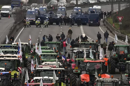 Tractors face military vehicles on a blocked highway, Wednesday, Jan. 31, 2024 in Chilly-Mazarin, south of Paris. Farmers have captured France's attention by showering government offices with manure and besieging Paris with traffic-snarling barricades of tractors and hay bales. Protesters say it's becoming harder than ever to make a decent living from their fields, greenhouses and herds. (AP Photo/Thibault Camus)