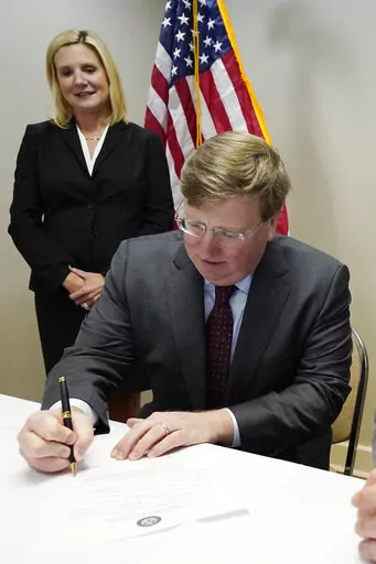 With wife Elee Reeves, watching, Mississippi Gov. Tate Reeves, signs his qualifying papers to run for reelection at the party headquarters in Jackson, Tuesday, Jan. 3, 2023. (AP Photo/Rogelio V. Solis)