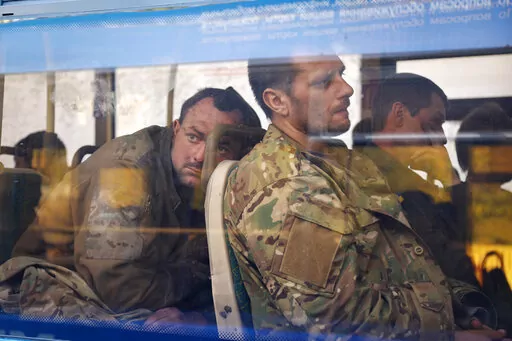 Ukrainian servicemen sit in a bus after they were evacuated from the besieged Mariupol's Azovstal steel plant, near a remand prison in Olyonivka, in territory under the government of the Donetsk People's Republic, eastern Ukraine, Tuesday, May 17, 2022. Breaking its silence on prisoners of war, the Red Cross said Thursday, May 19, 2022 it has registered “hundreds” of Ukrainian prisoners of war who left the giant Azovstal steel plant in Mariupol after holding out in a weeks-long standoff with