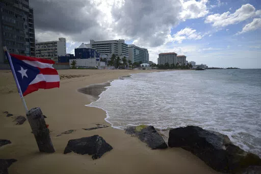 A Puerto Rican flag flies on an empty beach at Ocean Park, in San Juan, Puerto Rico, Thursday, May 21, 2020.  Puerto Rico’s nearly five-year bankruptcy battle was resolved Tuesday, Jan. 18, 2022, after a federal judge signed a plan that slashes the U.S. territory’s public debt load as part of a restructuring and allows the government to start repaying creditors. (AP Photo/Carlos Giusti, File)