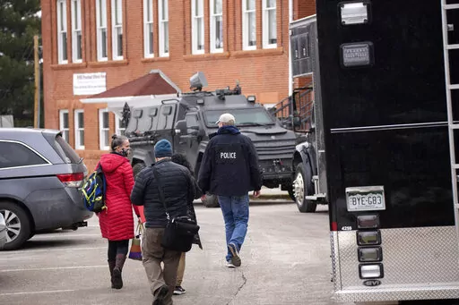 Police vehicles sit in front of University Hill Elementary School across from the campus of the University of Colorado after Matthew Harris,  accused of making violent threats against the college as well as the University of California, Los Angeles, was taken into custody following a standoff at his Boulder apartment complex Tuesday, Feb. 1, 2022, in Boulder, Colo. A trail of red flags about his behavior toward women followed Harris, a former lecturer at UCLA, on an academic journey that took hi