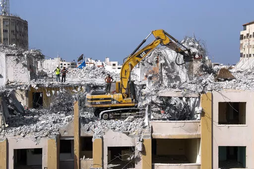 Palestinian workers use a backhoe to break and remove parts of the Al-Jawhara building, that was damaged in Israeli airstrikes during Israel's war with Gaza's Hamas rulers last May, in the central al-Rimal neighborhood of Gaza City, Nov. 16, 2021. The Gaza Strip has few jobs, little electricity and almost no natural resources. But after four bruising wars with Israel in just over a decade, it has lots of rubble. Local businesses are now finding ways to cash in on the chunks of smashed concrete, 