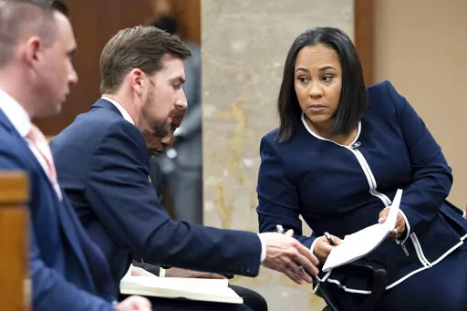 Fulton County District Attorney Fani Willis, right, talks with a member of her team during proceedings to seat a special purpose grand jury in Fulton County, Georgia, on Monday, May 2, 2022, to look into the actions of former President Donald Trump and his supporters who tried to overturn the results of the 2020 election. The hearing took place in Atlanta. (AP Photo/Ben Gray)