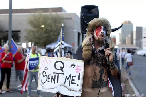 Jacob Anthony Chansley, who also goes by the name Jake Angeli, a Qanon believer speaks to a crowd of President Donald Trump supporters outside of the Maricopa County Recorder's Office where votes in the general election are being counted, in Phoenix on Nov. 5, 2020. From the Salem witch trials to fears of the Illuminati to the Red Scare to QAnon, conspiracy theories have always served as dark counter programming to the American story taught in history books. (AP Photo/Dario Lopez-Mills, File)