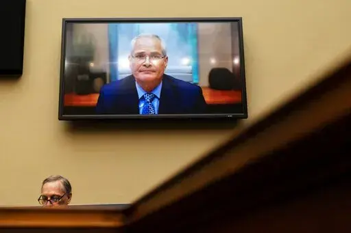 Darren Woods, CEO of ExxonMobil, testifies via video conference during a House Committee on Oversight and Reform hearing on the role of fossil fuel companies in climate change, Oct. 28, 2021, with Rep. Ralph Norman, R-S.C., at left, on Capitol Hill in Washington.  House Democrats are accusing oil companies of “ripping off the American people” and putting profits before production as Americans suffer from higher gasoline prices amid the war in Ukraine. Oil executives, testifying before Congre