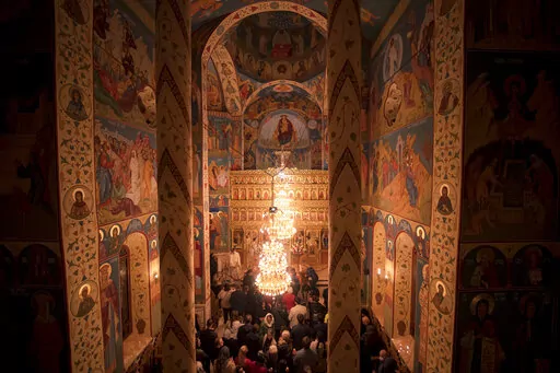 Orthodox worshipers hold candles during the Easter religious service at the Brancusi Parish Church in Bucharest, Romania, Sunday, April 24, 2022. The religious service was also attended by dozens of Ukrainian refugees living in a social center belonging to the church. (AP Photo/Andreea Alexandru)