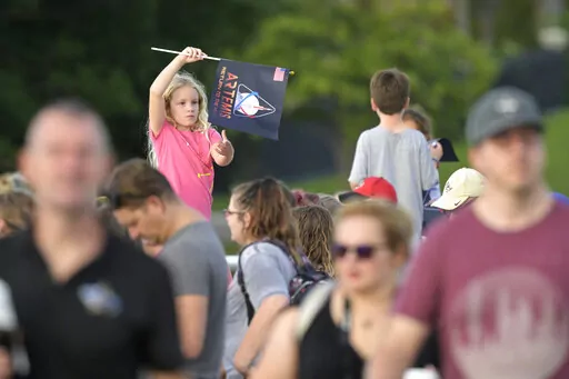 A child waves a souvenir flag while waiting on the Max Brewer Bridge to view the launch on Pad 39B for the Artemis I mission to orbit the moon at the Kennedy Space Center, Monday, Aug. 29, 2022, in Titusville, Fla. The launch was scrubbed. (AP Photo/Phelan M. Ebenhack)