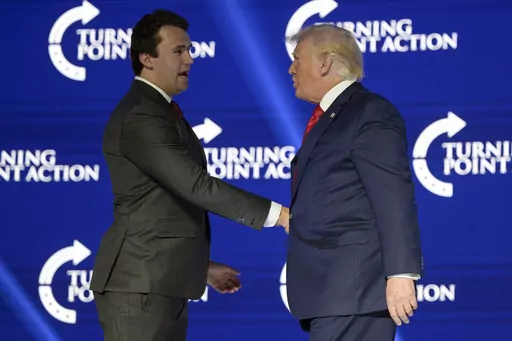 Former President Donald Trump, right, shakes hands with Turning Point CEO Charlie Kirk before speaking during the Turning Point USA Student Action Summit, July 23, 2022, in Tampa, Fla. The nonprofit rocketed to prominence by latching on to Trump’s 2016 campaign and has raised roughly a quarter-billion dollars since, much of it spent cultivating conservative influencers and hosting glitzy events. The organization also enriched Kirk and his allies, according to an Associated Press review of publ
