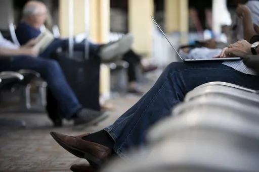 This June 2, 2021, photo shows a person working on a laptop at Ronald Reagan Washington National Airport in Arlington, Va. President Biden derided “junk fees” during his State of the Union Address, calling out airline seat selection fees in particular. Politicians and travelers have been railing against these unexpected add-on fees — like upcharges for seat selection and resort fees — for years. (AP Photo/Jenny Kane, File)