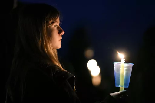 A local resident prays during a candlelight vigil following a shooting at Perry High School, Jan. 4, 2024, in Perry, Iowa. An Iowa principal who put himself in harm's way to protect students during a school shooting earlier this month has died. Caldwell Parrish Funeral Home & Crematory confirmed the death of Perry High School Principal Dan Marburger after the family announced it on a GoFundMe page. Marburger died Sunday morning, Jan. 14 after he was critically injured during the Jan. 4 attack. (