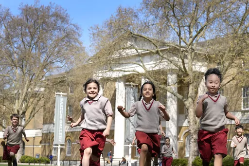 Pupils from Hill House School in London, play on the grass in front of the now Saatchi Gallery, where Britain's King Charles III played sport as a pupil, Thursday, April 20, 2023. King Charles III hasn’t even been crowned yet, but his name is already etched on the walls of Hill House School in London. A wooden slab just inside the front door records Nov. 7, 1956, as the day the future king enrolled at Hill House alongside other notable dates in the school’s 72-year history. (AP Photo/Kirsty 