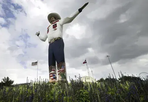 Bluebonnets, the state flower of Texas, surround Big Tex as storm clouds move in above, Friday, Sept. 27, 2013, in Dallas. (AP Photo/Tony Gutierrez, File)