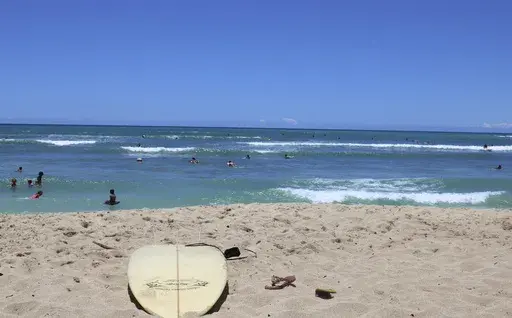 A surfboard lies on the sand on the sand at a beach known as White Plains in Ewa Beach, Hawaii, May 12, 2023. A judge has halted plans for an artificial wave pool until developers can revise an environmental assessment to address concerns raised by Native Hawaiians and others who say the project is unnecessary in the birthplace of surfing and a waste of water. (AP Photo/Jennifer Sinco Kelleher, File)